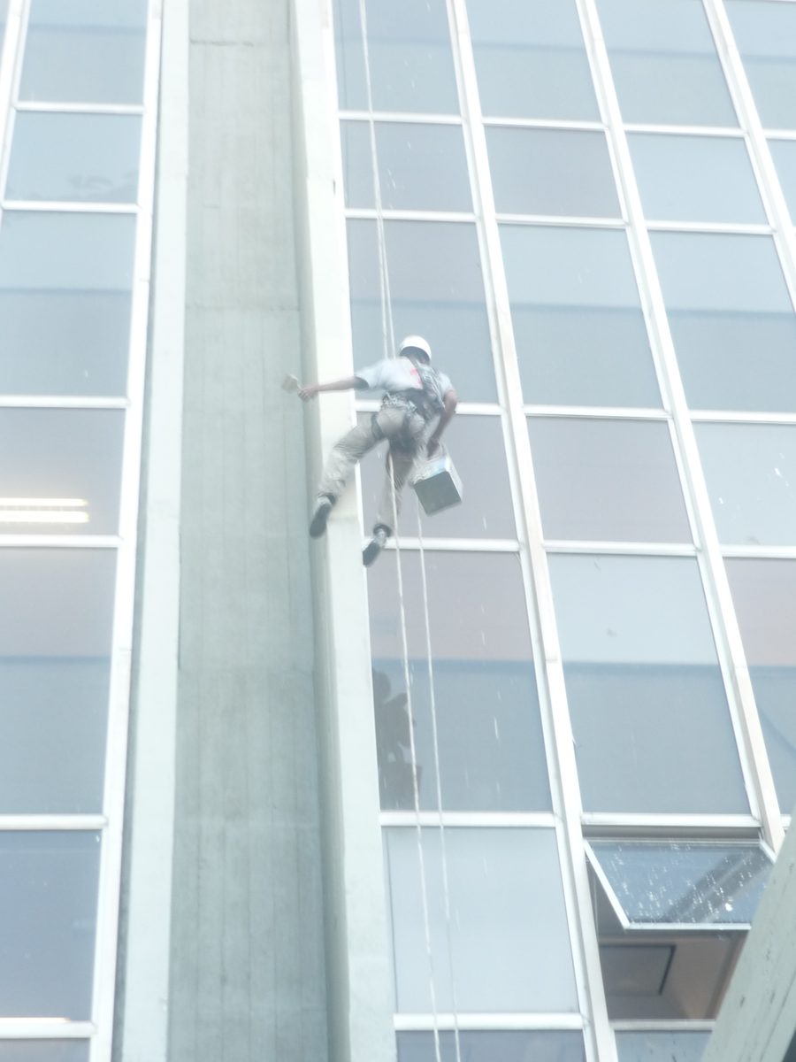 Profissional realizando pintura de fachada com acesso por cordas